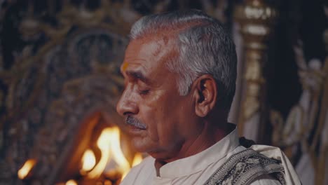 elderly indian priest chanting vedic mantras, meditating with closed eyes amid glowing temple candles, embodying spiritual devotion and traditional religious practice