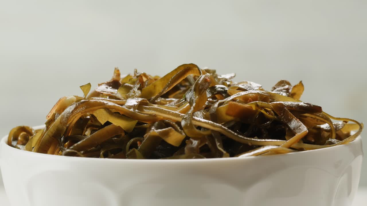 Japanese wakame sea weed laminaria chuka fermented food. Close-up on a detail of Hiyashi Wakame Chuka or seaweed salad or seaweed with sesame seeds on a plate. Top view. Seafood background.