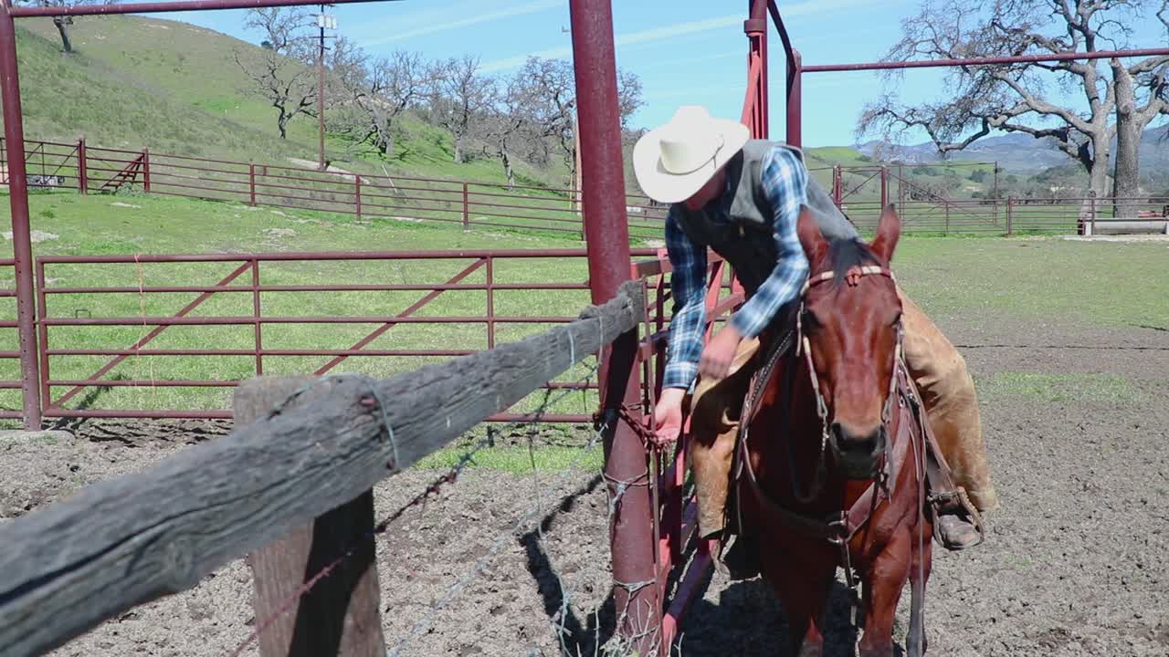 un vaquero abre una puerta roja para comenzar su duro día de trabajo