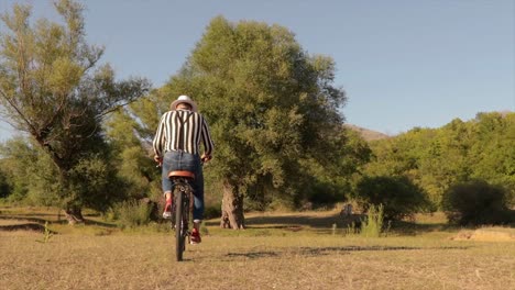 young handsome hipster man riding a bike in nature