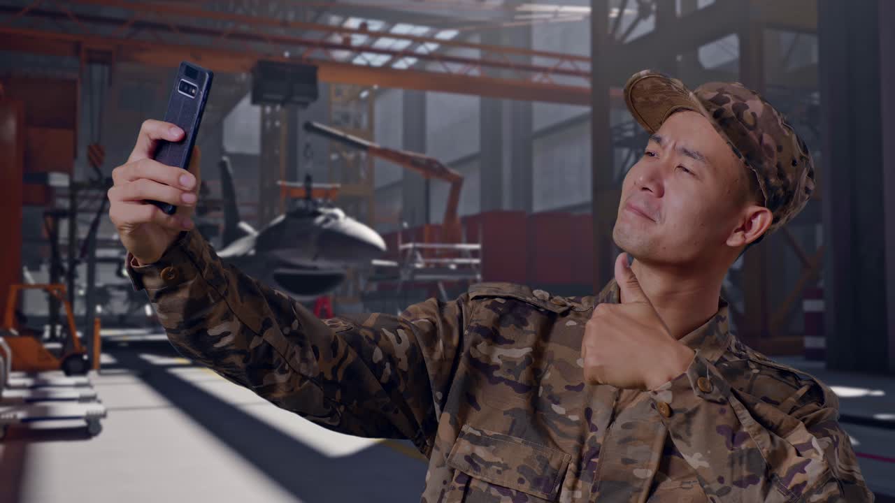 Soldato sorridente in mimetica che si scatta un selfie in un hangar per aerei