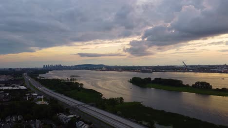 Aerial-landscape-view-of-Montreal,-Canada,-over-water-flowing-in-a-river,-at-sunset