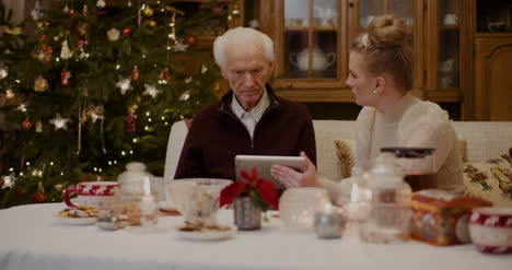 grandfather talking while granddaughter holding digital tablet 3