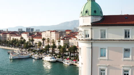 revealing shot of riva waterfront boardwalk behind port authority building in split city, croatia