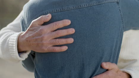 close up of an unrecognizable senior man hands hugging his wife