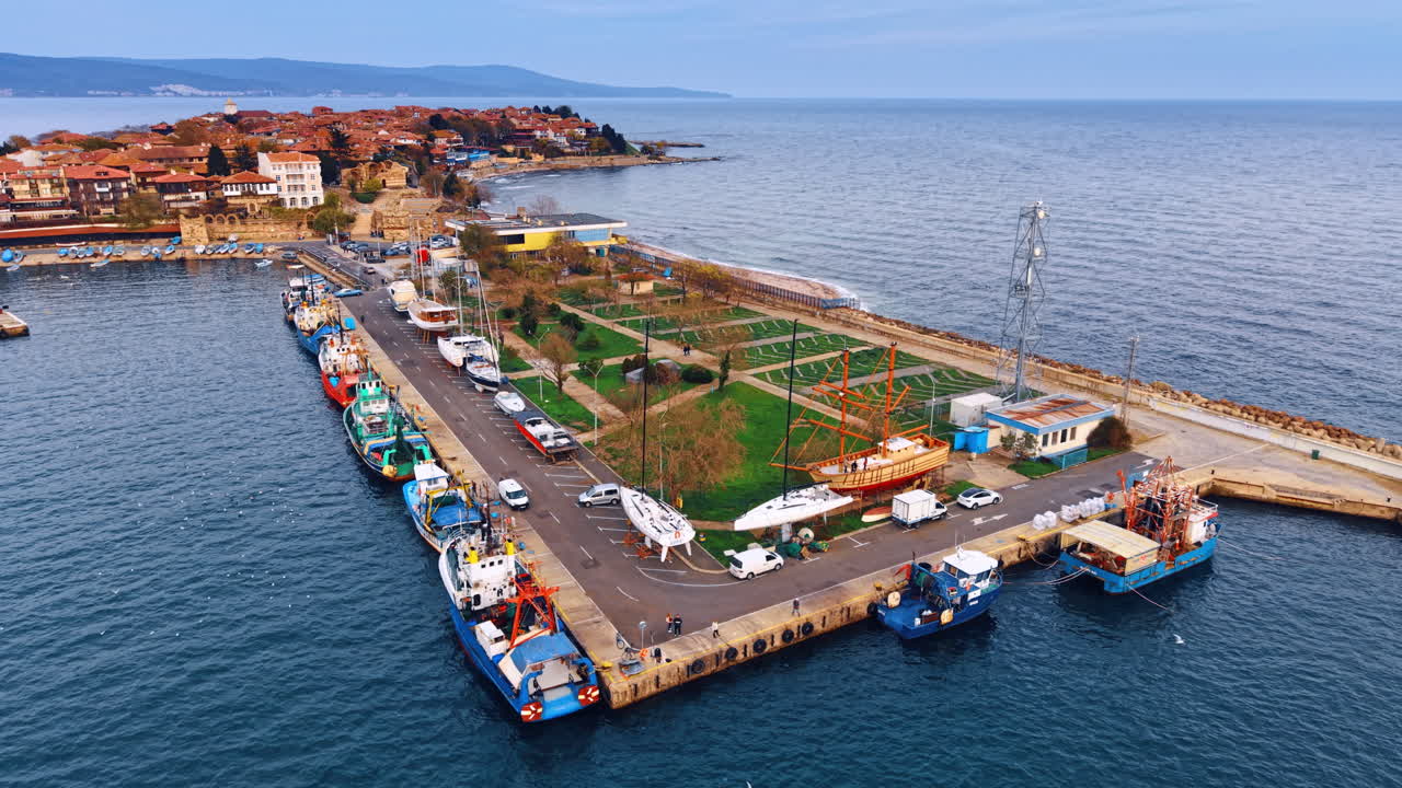 Banchina con campi verdi e un parco circondata da barche e yacht. Skyline con tetti rossi di Nesebar, Bulgaria, sullo sfondo.