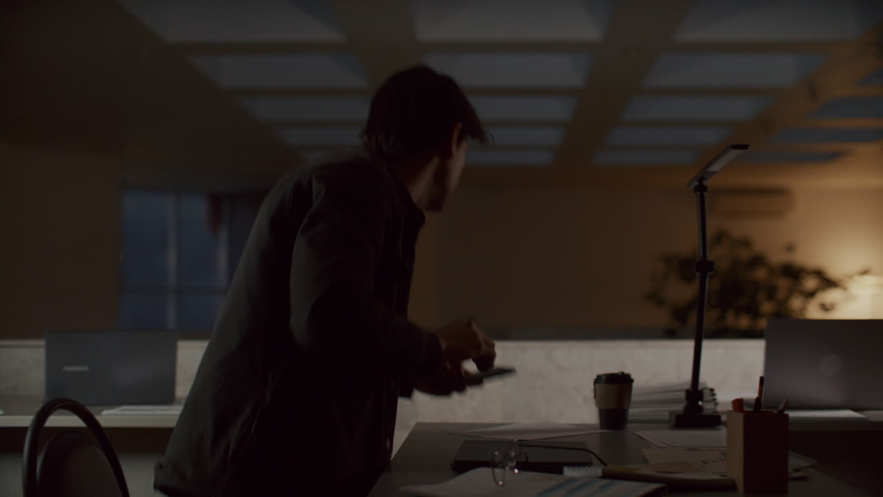 Young Man Finishing Work on Laptop and Leaving Office at Night