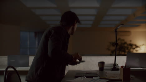 young man finishing work on laptop and leaving office at night