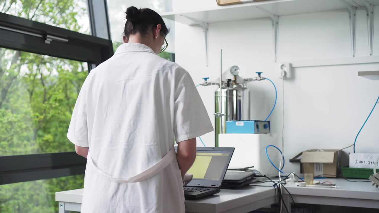 Donna in laboratorio che controlla una provetta con un campione di sangue, sfondo naturale, vista frontale centrale