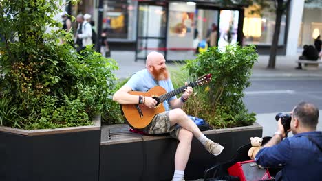 musician performs while being photographed on a busy street