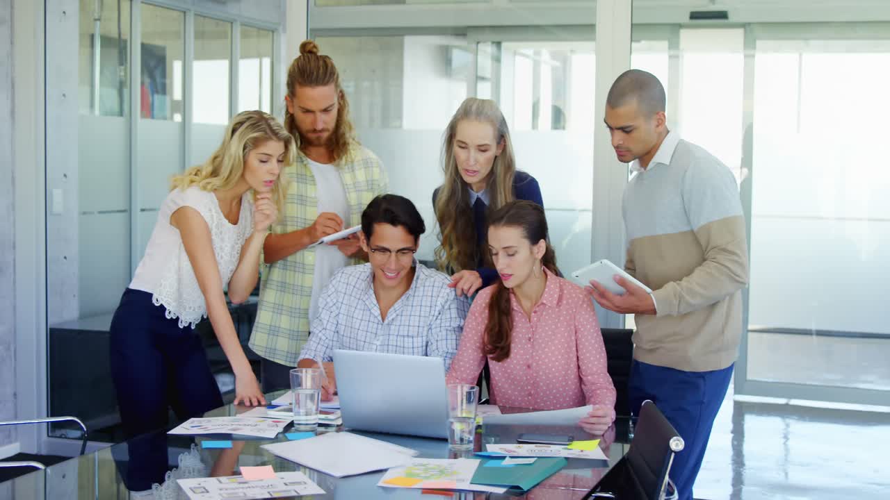 colegas discutiendo sobre la computadora portátil en la mesa 4k