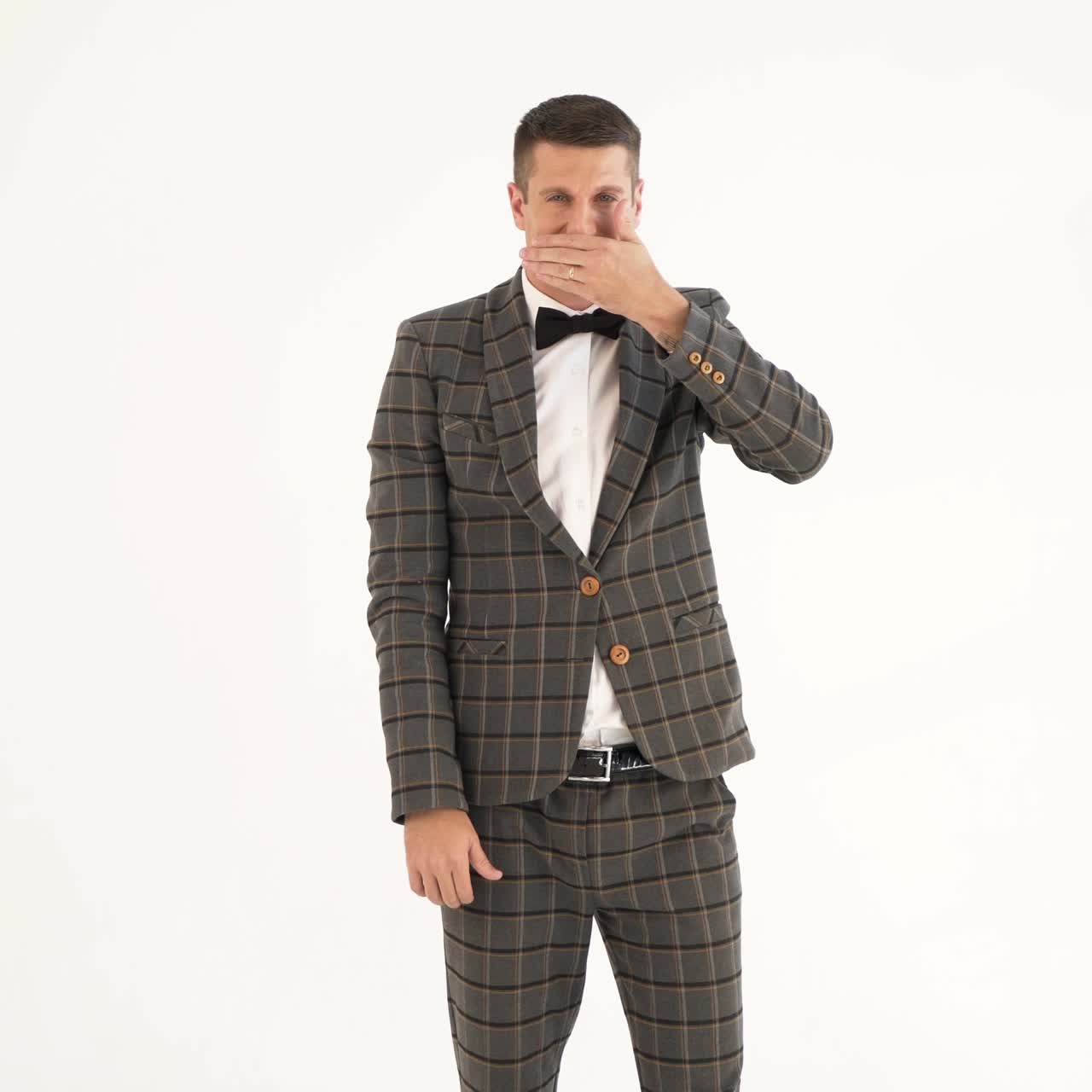 talented showman is holding his hand in front of his face and showing sad and funny emotions with his face in a white background
