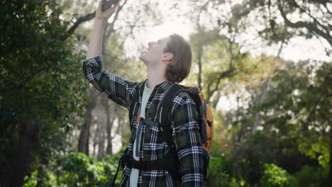 man trying to get phone signal in the forest