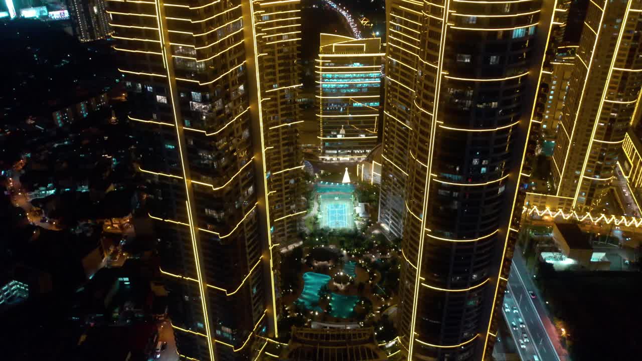 Aerial video of Rockwell Center skyscrapers in Makati, Metro Manila, glowing with lights at night and surrounded by the vibrant energy of the city skyline.