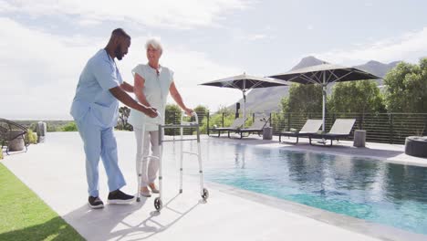 video of happy african american male doctor taking care of caucasian senior woman in garden