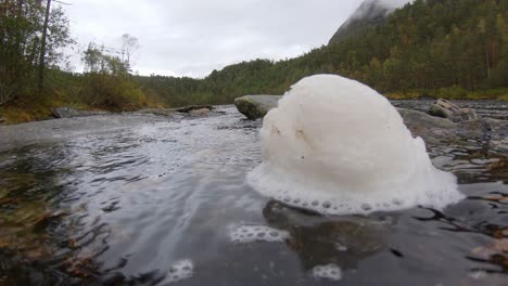 Primer-Plano-De-Una-Pieza-Fresca-De-Espuma-Giratoria-En-La-Parte-Superior-Del-Río-Que-Fluye---Día-Nublado-En-El-Río-Forestal-Escandinavia