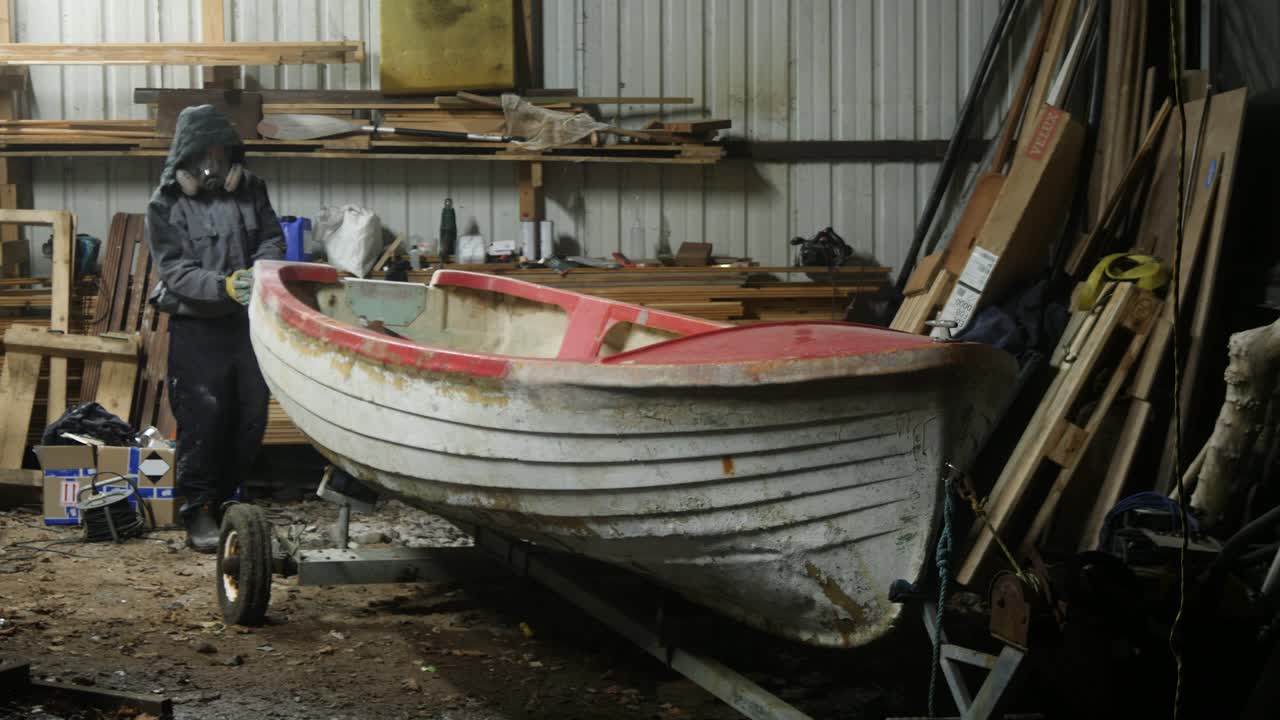 Sanding shaping fiberglass transom of lake boat, Wide shot