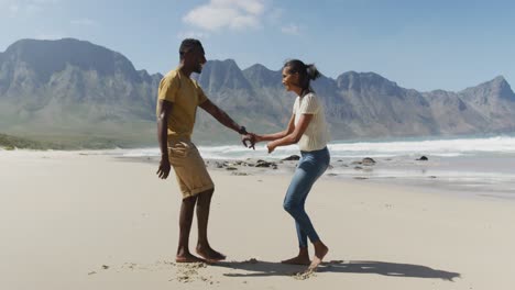 happy african american couple dancing together at the beach