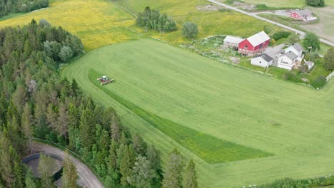 Traktor-Schneidet-Grünes-Gras-Auf-Dem-Weiten-Feld-In-Der-Nähe-Des-Bauernhauses