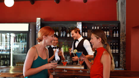 dos mujeres con bebidas cócteles hablando entre sí en el mostrador