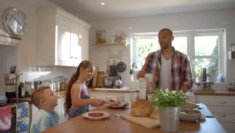 father and children at home eating breakfast in kitchen