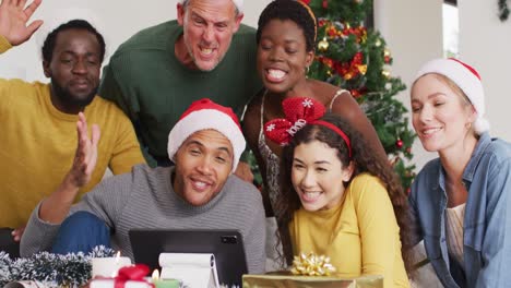 Happy-group-of-diverse-friends-using-tablet-for-video-call-at-christmas-party