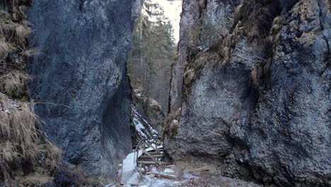 drone approaching on steep rocky mountains in winter forest