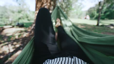 female relaxing in hammock with glass of wine at secluded wood cabin in forest