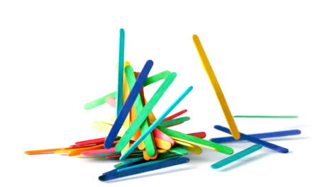 Colourful-wooden-sticks-falling-on-white-surface