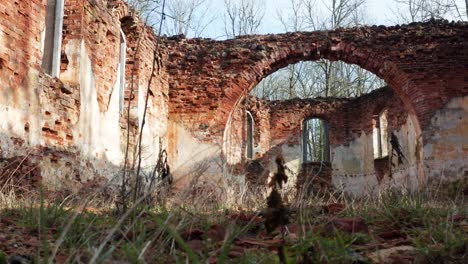 vista de bajo ángulo con hierba de la iglesia abandonada pared de ladrillo forma de arco interior