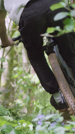 Close-Up-Vertical-Video-Of-Man-On-Mountain-Bike-Cycling-Along-Dirt-Trail-Through-Woodland