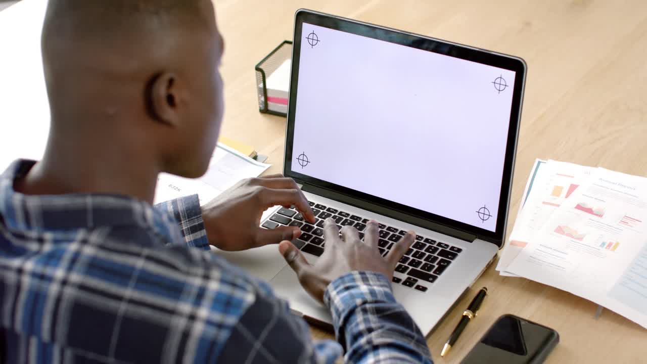 African american man sitting at table using laptop with copy space on screen at home, slow motion