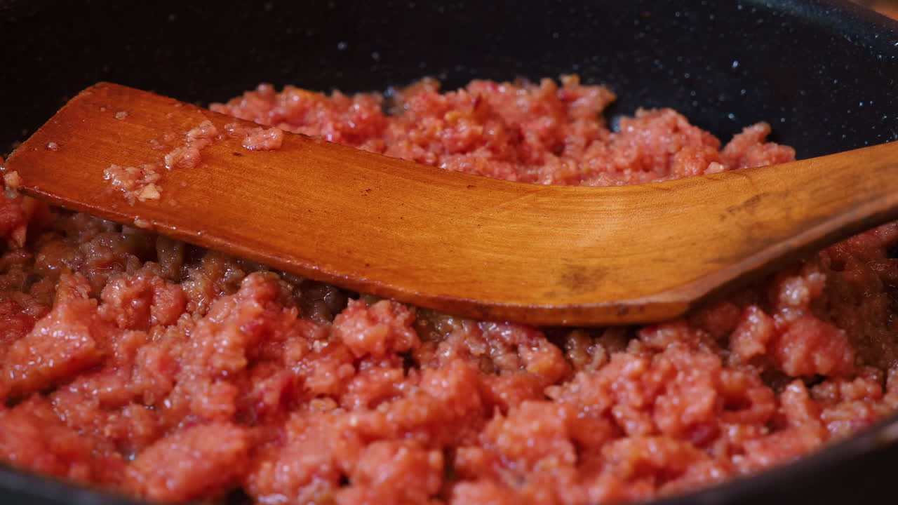 cocinar carne con cuchara de madera en una sartén
