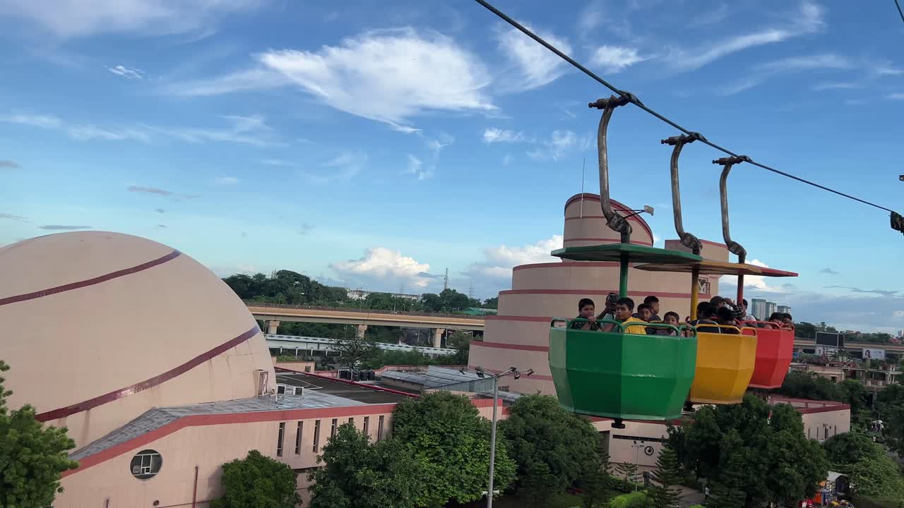 View of packed up cable car of science city from another cable car of science city park with cityscape in the background.