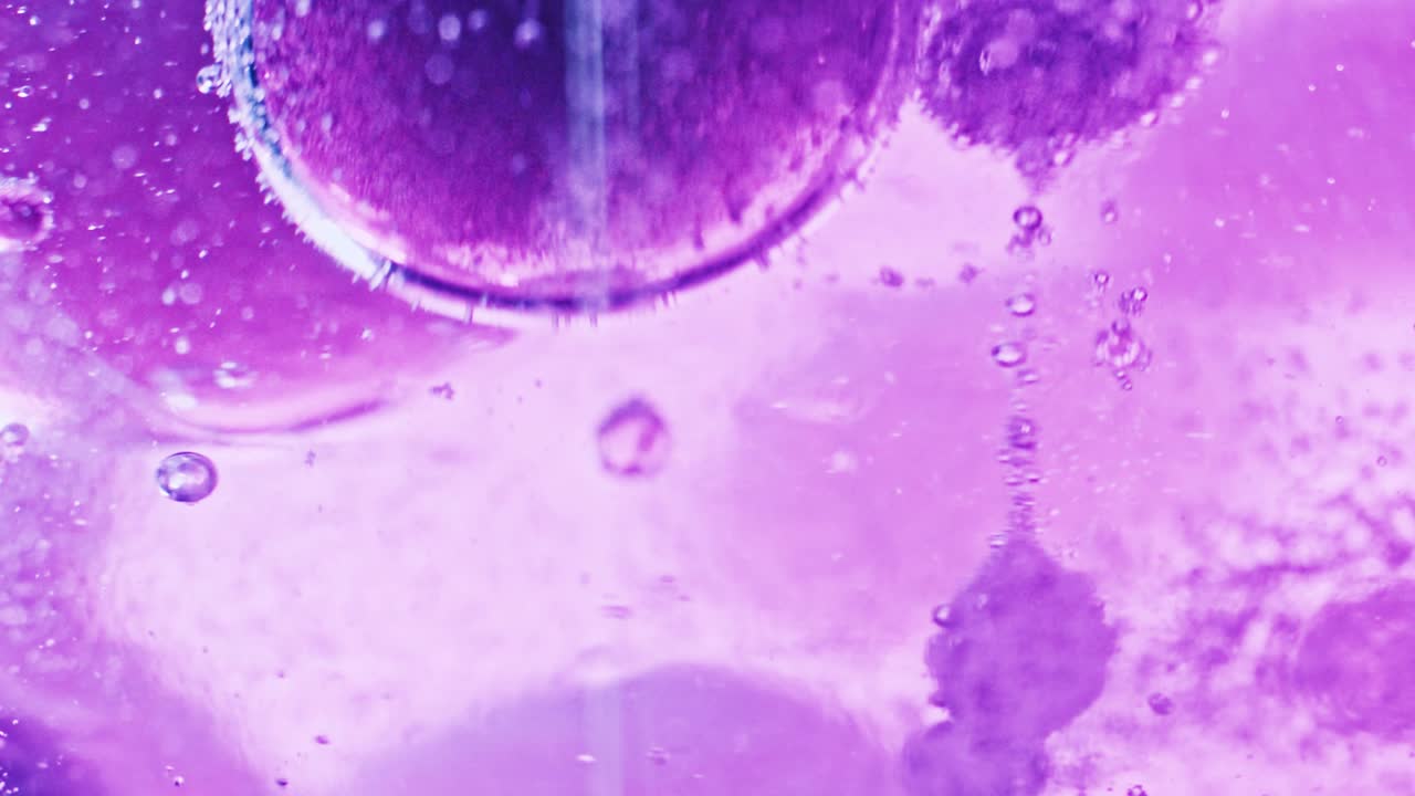 foto macro de bolhas violetas grandes e pequenas flutuando e pingando em água violeta brilhante