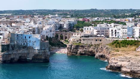 aerial view slowly revealing the beautiful beach of lama monachile and the city of polignano a mare, italy