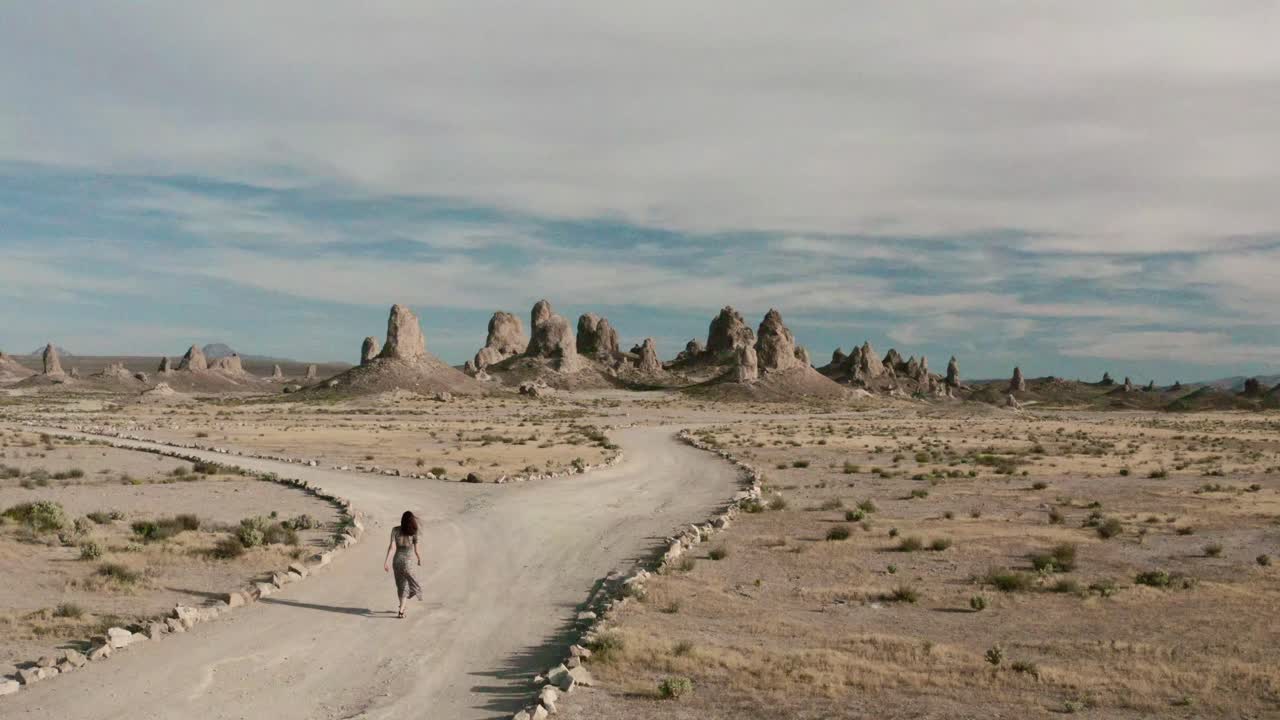 A woman is hiking on a trail towards a stunning rock formation landscape