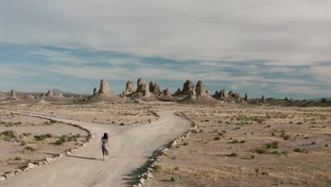 a woman is hiking on a trail towards a stunning rock formation landscape