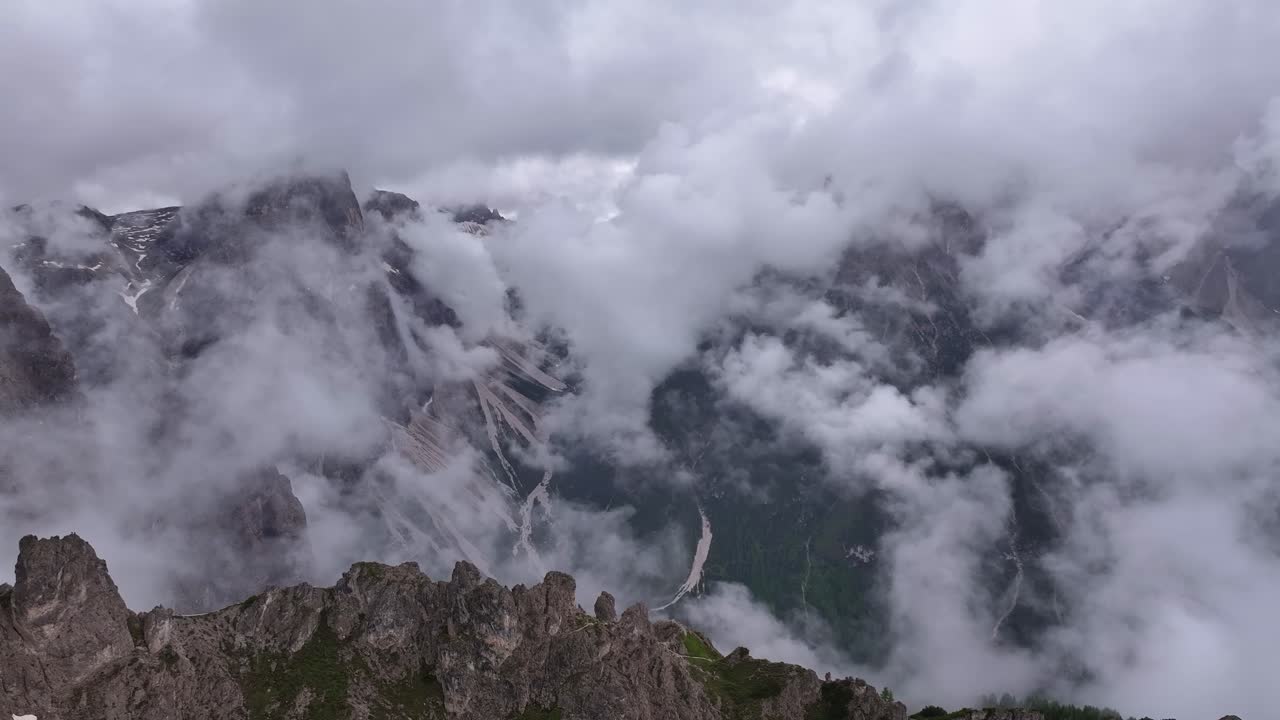Drone pans right over Rotwandwiesen peaks, capturing clouds flowing through mountain valleys in a scenic vista in Italian Alps