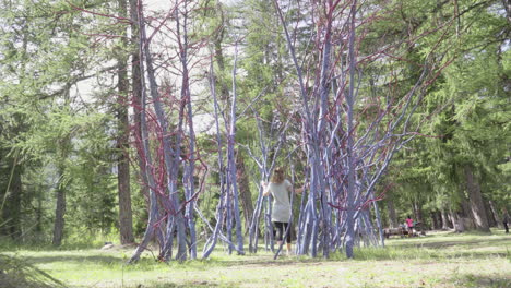 girl goes through a sculpture of colorful trees in a italian forest, 4k