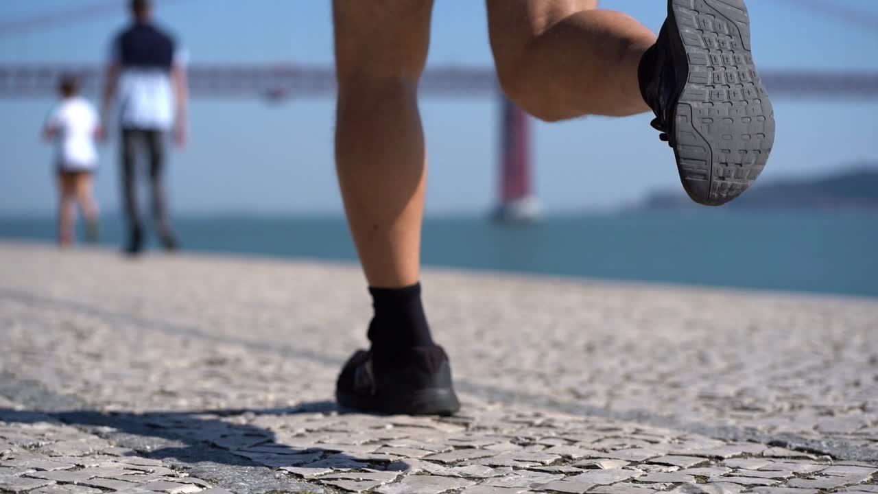 piernas de un hombre maduro corriendo por el pavimento a la orilla del río