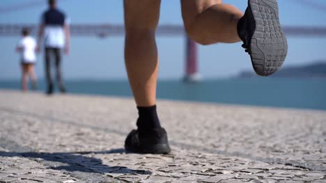 legs of mature man running on pavement at riverside