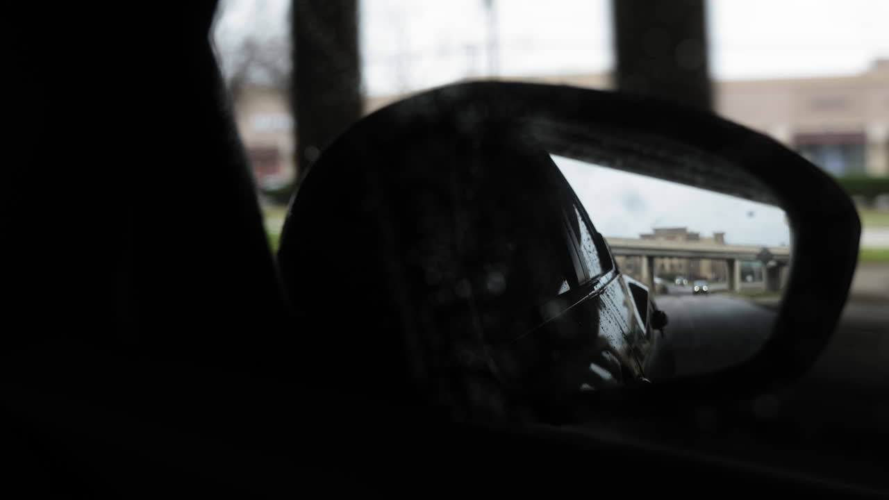 POV looking in to the passenger rearview mirror in a modern sedan, driving under an overpass