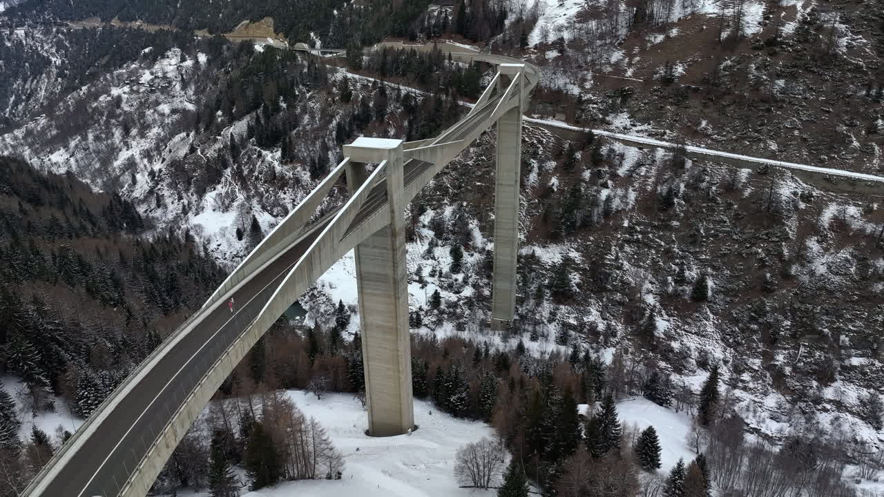 겨울철 스위스의 높은 현대식 갠터 다리를 자동차가 운전합니다.