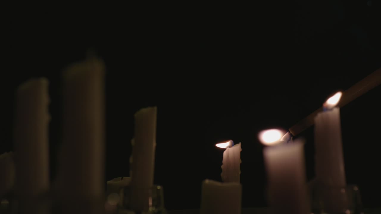 Un primissimo piano di candele bianche accese con uno sfondo nero