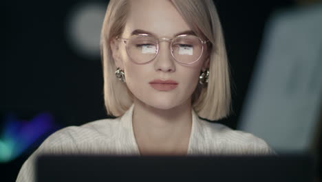 Serious-business-woman-working-on-laptop-computer-in-dark-office.