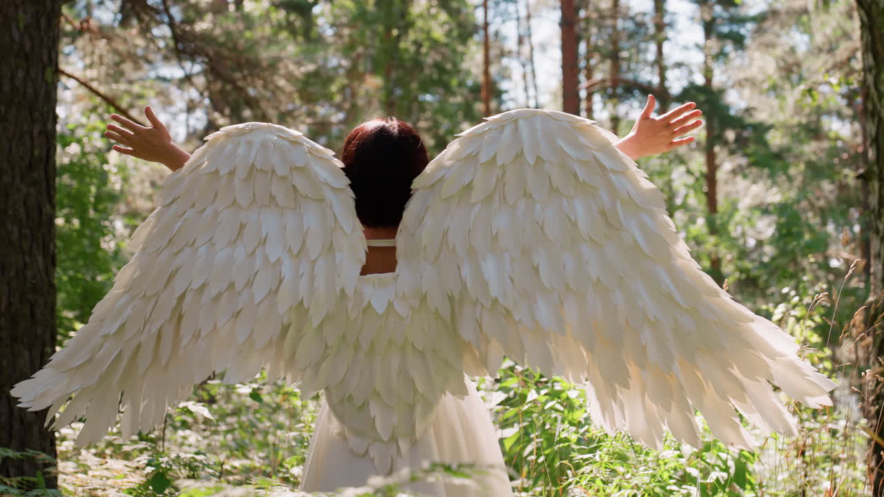 Fairy goddess with radiant white wings spreads arms under warm sunlight surrounded by lush forest, smiling with joy as she turns gracefully, sunlight illuminating feathers