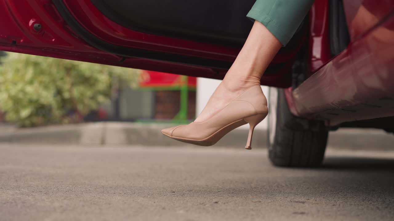 dama en elegantes zapatos de tacón alto sale de la puerta de apertura del coche