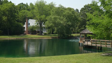 captures the serene beauty of a picturesque lake featuring a charming white pavilion in the middle of the water, with a pristine white house nestled along the