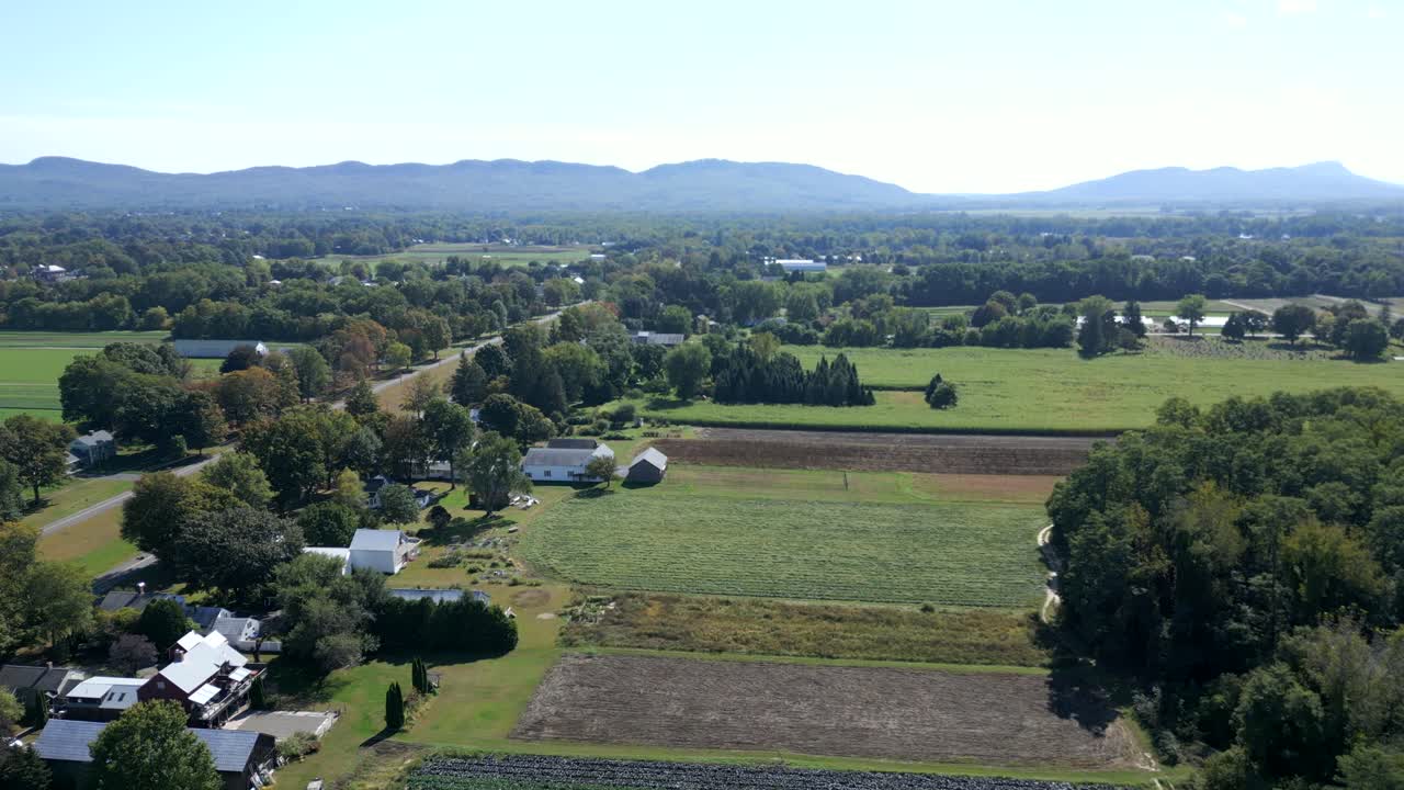 Panning drone fly at Alexandra Dawson Conservation Area on wide countryside fields with mountains and houses, Hadley, Massachusetts, USA